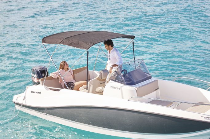 Pareja disfrutando y fondeados en embarcacion de alquiler 6 metros debajo de toldo bimini.